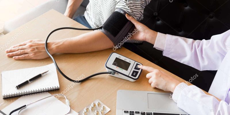 healthcare, hospital and medicine concept - doctor and patient measuring blood pressure by machine.